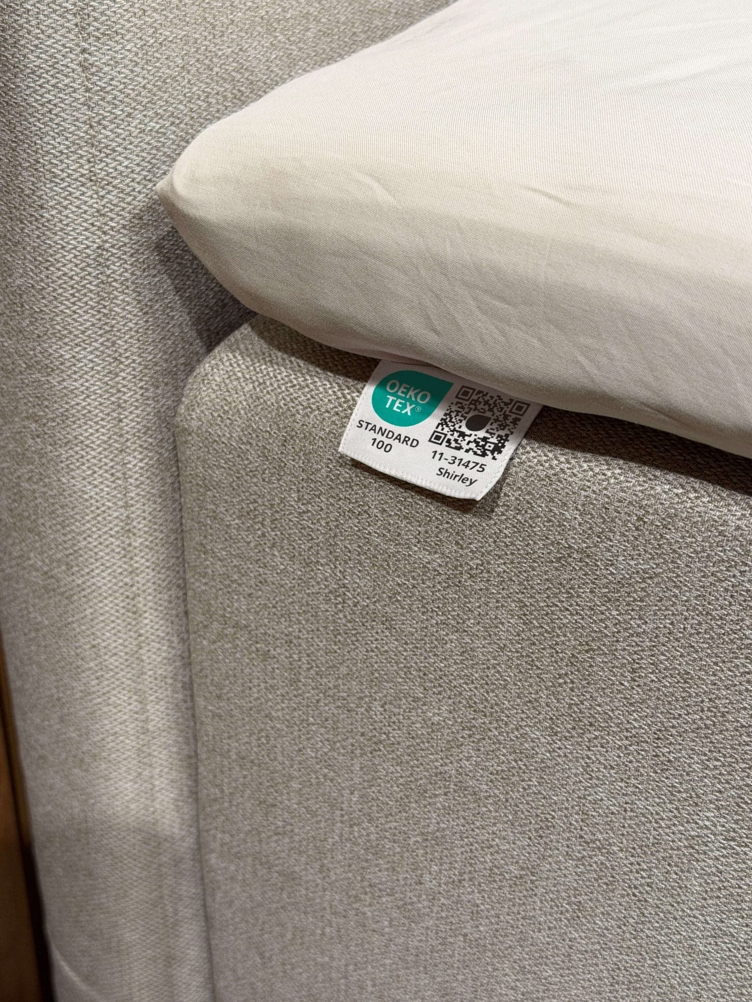 OEKO-TEX® STANDARD 100-merke sydd fast i sengens beige stoff under lakenet